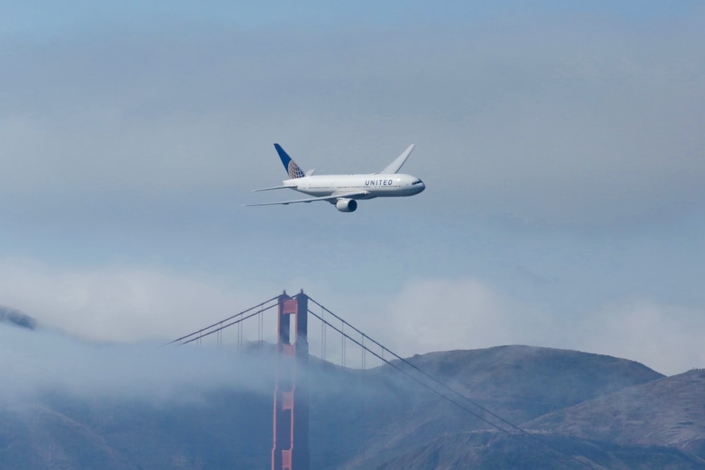 A United Airlines jet flies over the Golden Gate Bridge.