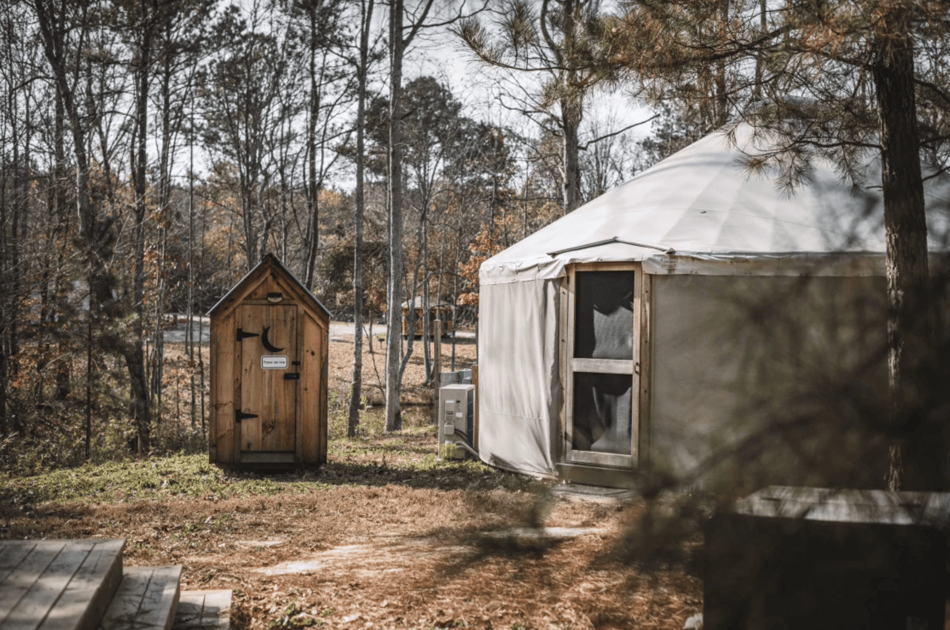 A yurt in the woods nextto an outhouse