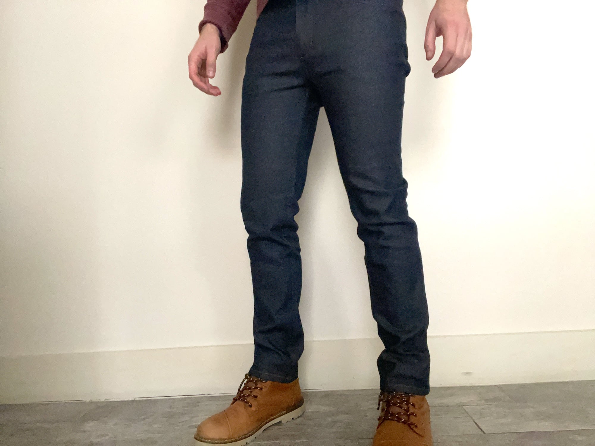A guy wears a pair of Mack Weldon jeans standing against a white wall